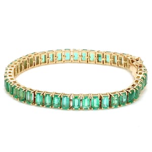 Könnte beinhalten: Ein goldenes Armband mit einer Reihe rechteckiger smaragdgrüner Edelsteine.