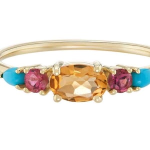 Peut inclure: Une bague en or avec une grande pierre précieuse orange de forme ovale entourée de deux petites pierres roses et de deux pierres turquoise.