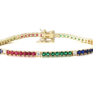 May include: A gold bracelet featuring a line of colourful gemstones. The gemstones are arranged in a pattern of blue, red, green, and white. The bracelet has a clasp closure.