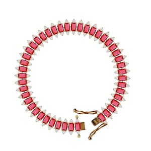 May include: A gold bracelet with a row of red rectangular gemstones and smaller clear gemstones. The bracelet has a clasp.