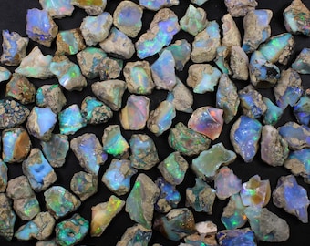 May include: A collection of rough opal stones in various shades of blue, green, and white. The stones are irregular in shape and have a natural, unpolished finish.