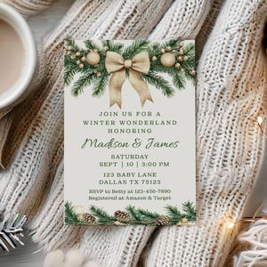 May include: A winter wonderland invitation with text that reads "Join us for a Winter Wonderland honoring Madison & James". The invitation is decorated with pine branches, a bow, and pinecones. A mug of coffee, pinecones, and a lit candle are also present.