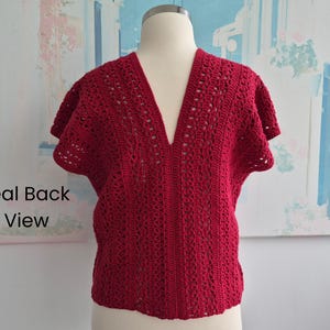 Puede incluir: Una blusa de crochet roja de manga corta con cuello en V profundo. La blusa se muestra en un maniqu&iacute;, mostrando la vista trasera. El patr&oacute;n de crochet presenta detalles calados, agregando textura e inter&eacute;s visual a la prenda.