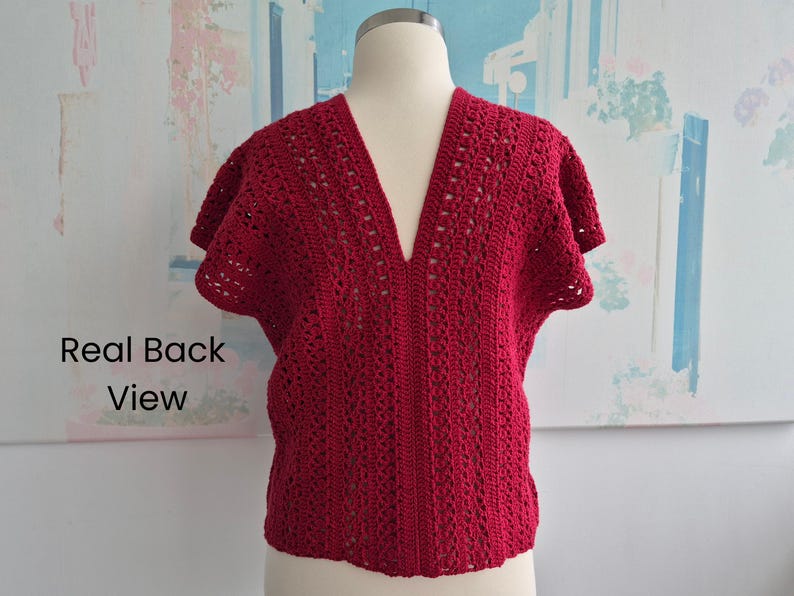 Puede incluir: Una blusa de crochet roja de manga corta con cuello en V profundo. La blusa se muestra en un maniqu&iacute;, mostrando la vista trasera. El patr&oacute;n de crochet presenta detalles calados, agregando textura e inter&eacute;s visual a la prenda.