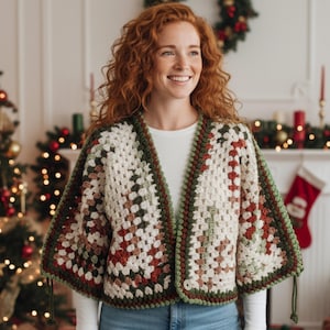 May include: A cream, green, and red crochet cape in a granny square pattern. The open-front cape has a dark green border. This handmade garment is a stylish layering piece. The cape is a cozy addition to any wardrobe, perfect for the colder months.