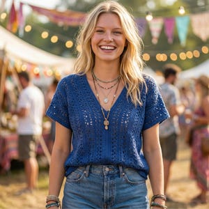 Puede incluir: Una mujer sonr&iacute;e, vistiendo un top azul de crochet con cuello en V y pantalones cortos de mezclilla. Lleva varios collares y pulseras. El fondo muestra un festival con tiendas de campa&ntilde;a y luces.