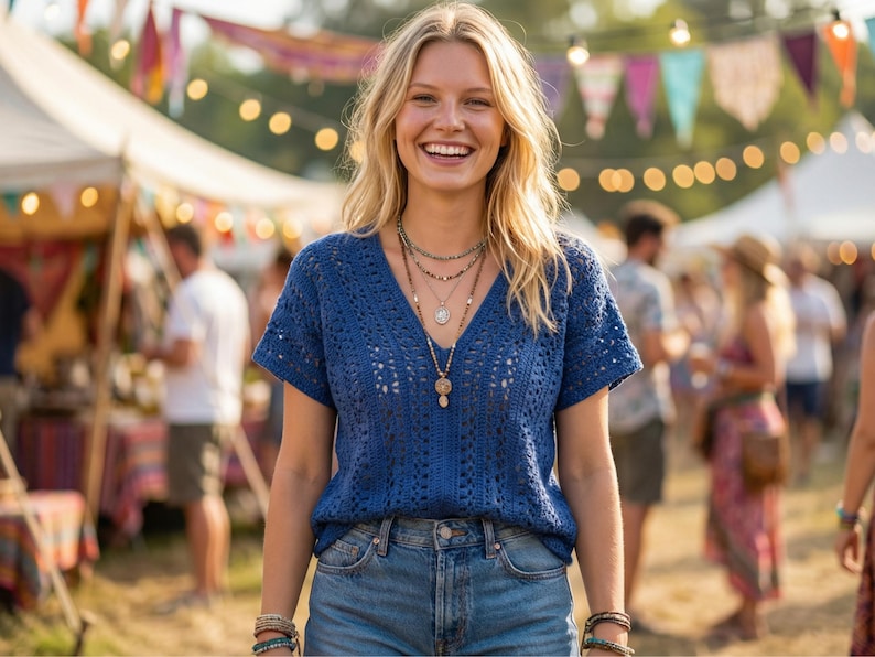 Puede incluir: Una mujer sonr&iacute;e, vistiendo un top azul de crochet con cuello en V y pantalones cortos de mezclilla. Lleva varios collares y pulseras. El fondo muestra un festival con tiendas de campa&ntilde;a y luces.