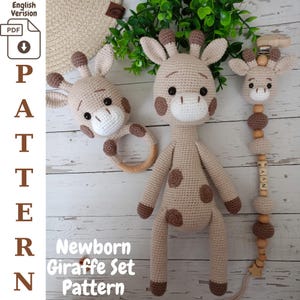 Könnte beinhalten: Ein gehäkeltes Neugeborenen-Giraffen-Set, bestehend aus einer Giraffe, einer Rassel und einem Schnullerclip. Das Set ist beige mit braunen Flecken und Akzenten. Die Giraffe hat einen langen Hals, kleine Ohren und eine weiße Schnauze. Die Rassel hat einen Holzring.