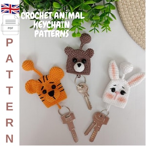 Può includere: Modelli di portachiavi animali all'uncinetto. L'immagine mostra tre portachiavi fatti a mano: una tigre arancione, un orso marrone e un coniglietto bianco. Ogni portachiavi è attaccato a un portachiavi argentato con una chiave. I portachiavi sono fatti di filato e hanno dettagliati tratti del viso.