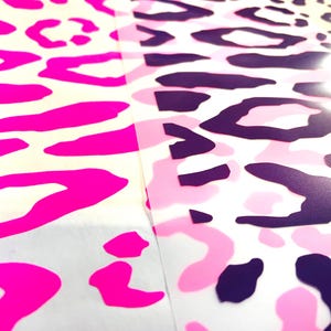 Könnte beinhalten: Nahaufnahme von drei verschiedenen Mustern: Zebrastreifen, pinkfarbene Leopardenflecken und rosa-violette Tarnflecken. Die Muster sind auf weißem Hintergrund gedruckt.
