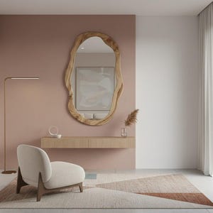 May include: A modern interior featuring a large, organic-shaped wooden mirror. Below the mirror is a floating wooden console with a small vase and decorative items. A cream-colored armchair and a geometric rug complete the space. A floor lamp provides soft lighting.