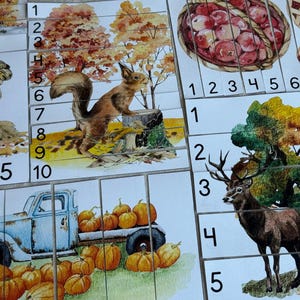 May include: Watercolor illustrations of autumn scenes. A squirrel on a tree stump, a deer, pumpkins in a truck, and apples in a basket are depicted. The images are divided into numbered squares, possibly for a game.