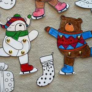 Puede incluir: Recortes de papel navide&ntilde;os dibujados a mano. Incluye un oso y un oso polar patinando sobre hielo, un regalo, un calcet&iacute;n y un &aacute;rbol de Navidad. Los osos visten ropa de invierno y patines de hielo. Los recortes son blancos con acentos coloridos.
