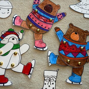 Op de afbeelding: Handgetekende kerstpapieren uitsparingen van beren en een ijsbeer die schaatsen, met truien en hoeden. Andere uitsparingen zijn een sneeuwpop, een kerstboom, een kous en een geschenkdoos.