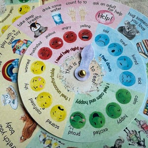 May include: A colorful, circular emotion chart with a rotating pointer. The chart features illustrations of various feelings like happy, sad, and angry, along with coping strategies. The text includes phrases like "I feel down" and "ask an adult for help."