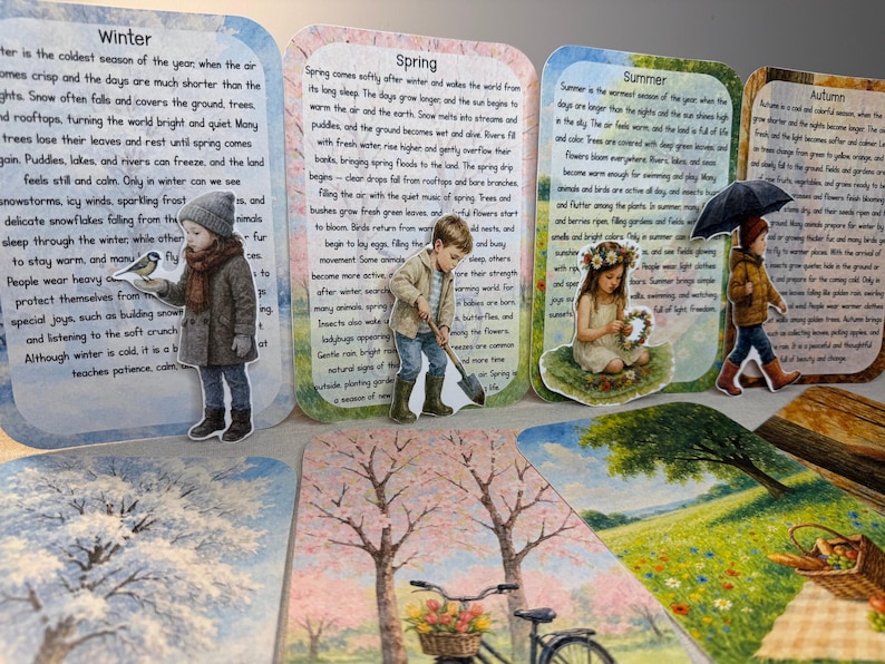 May include: A collection of illustrated cards depicting the four seasons: Winter, Spring, Summer, and Autumn. Each card features a child illustration and descriptive text about the season. The cards are arranged on a light-colored surface.