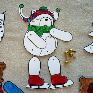 Puede incluir: Un kit de manualidades navide&ntilde;as caprichoso con un oso blanco que lleva un sombrero colorido y una bufanda verde, con patines rojos. Incluye un calcet&iacute;n navide&ntilde;o, un &aacute;rbol y recortes de cabeza de oso, junto con cierres dorados.