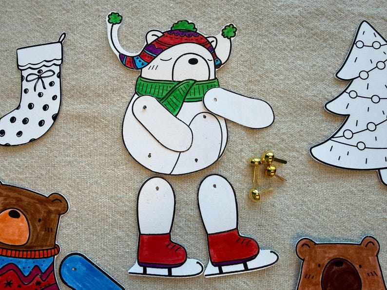 Puede incluir: Un kit de manualidades navide&ntilde;as caprichoso con un oso blanco que lleva un sombrero colorido y una bufanda verde, con patines rojos. Incluye un calcet&iacute;n navide&ntilde;o, un &aacute;rbol y recortes de cabeza de oso, junto con cierres dorados.