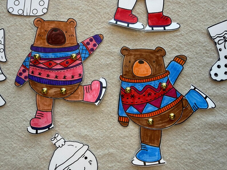 Puede incluir: Llaveros con forma de oso dibujados a mano con tem&aacute;tica invernal. Los osos visten jers&eacute;is coloridos y patines de hielo. Cada oso tiene ganchos dorados para llaves. Otros recortes con tem&aacute;tica invernal est&aacute;n en el fondo.