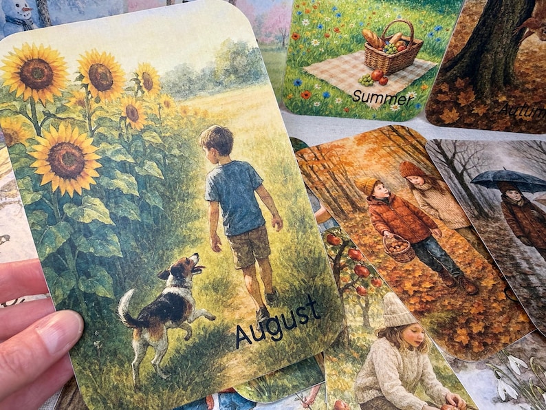 May include: A collection of seasonal art cards. One card features a boy and a dog in a field of sunflowers, labeled "August." Other cards depict scenes of summer, autumn, and winter. The cards have a watercolor style and are suitable for home decor or as gifts.