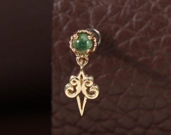 May include: A gold stud earring featuring a small, round, green gemstone set in a scalloped bezel. Below the stone hangs a gold charm with an intricate, symmetrical, openwork scroll design that tapers to a sharp, pointed tip at the bottom.