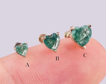 May include: Three gold heart-shaped earrings with green gemstone accents. The earrings are shown on a finger, with the smallest earring labeled 'A', the middle earring labeled 'B', and the largest earring labeled 'C'.