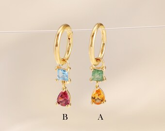 May include: Two gold hoop earrings with dangling charms. The charms feature a square gemstone and a teardrop-shaped gemstone. The earrings are labelled A and B.