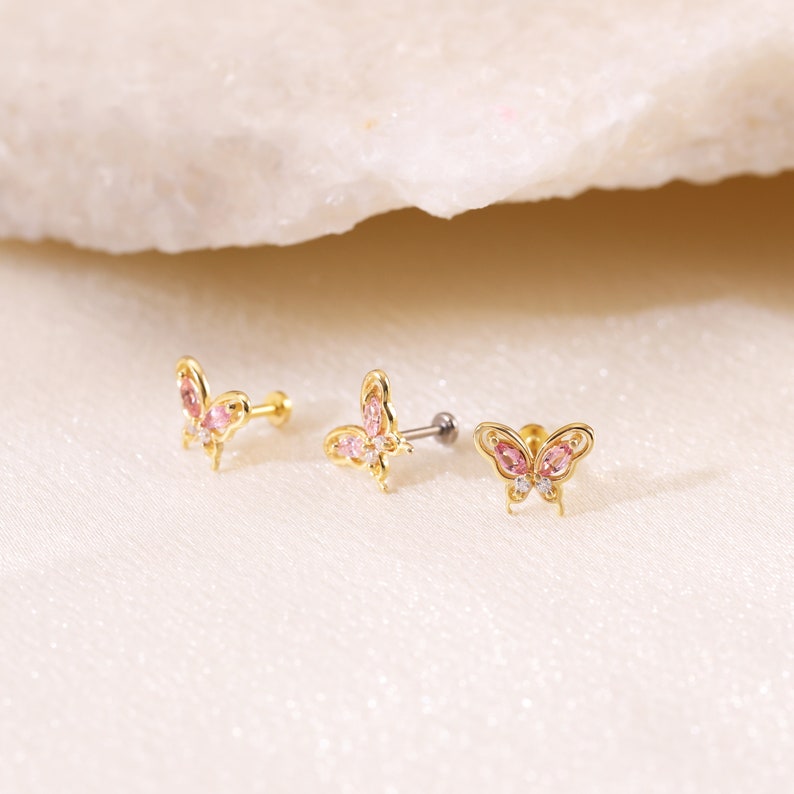 May include: Three gold butterfly body jewelry pieces with pink and clear gemstones. The butterflies are detailed with intricate designs.