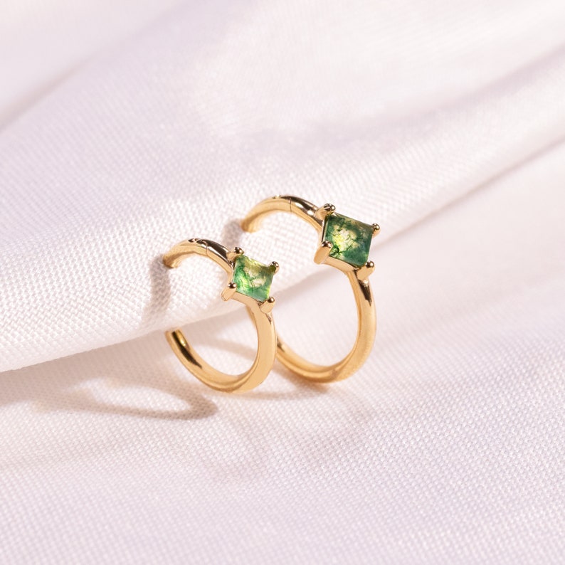 May include: A pair of gold hoop earrings with a square green stone set in each hoop.