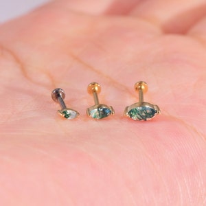 K&ouml;nnte beinhalten: Drei Ohrstecker mit einem marquisef&ouml;rmigen Moosachatstein. Die Ohrringe sind in verschiedenen Gr&ouml;&szlig;en erh&auml;ltlich, mit goldenen und silbernen Stiften. Die Moosachatsteine haben gr&uuml;ne und wei&szlig;e Einschl&uuml;sse.