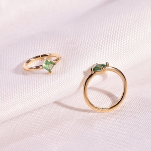 May include: Two gold hoop earrings with a square green gemstone set in each hoop.