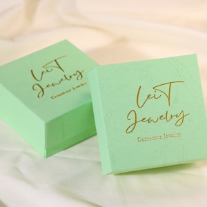 May include: Two light green jewelry boxes with gold lettering that reads "Leit Jewelry" and "Gemstone Jewelry".