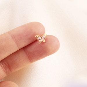 May include: A gold butterfly earring with pink and clear cubic zirconia stones.