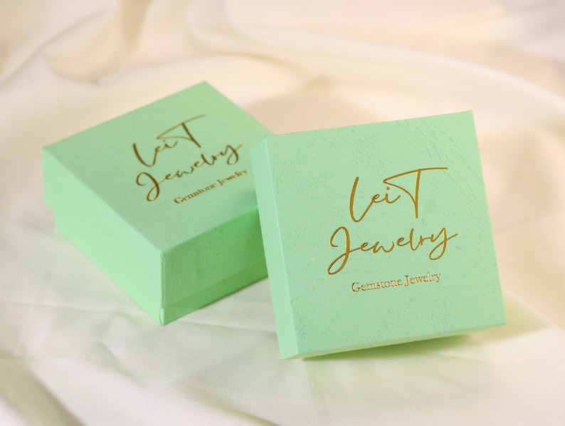 May include: Two light green jewelry boxes with gold lettering. The boxes say "Leit Jewelry" and "Gemstone Jewelry".
