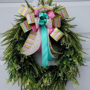 May include: A green wreath with a pink, green, and white plaid bow and a turquoise ribbon with white polka dots.