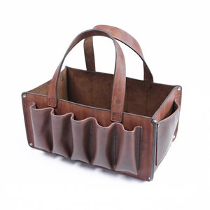 May include: A brown leather tote bag with multiple pockets and a single handle. The bag is empty and open.