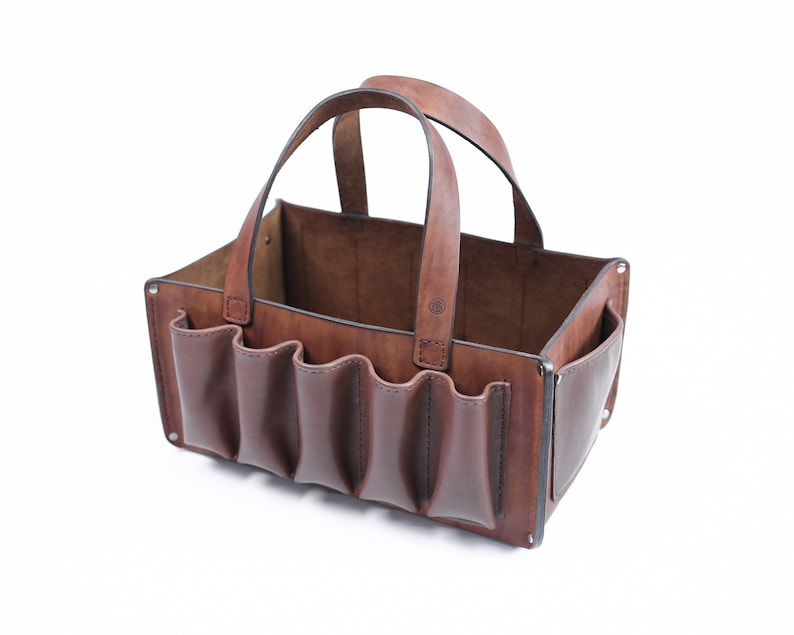 May include: A brown leather tote bag with multiple pockets and a single handle. The bag is empty and open.