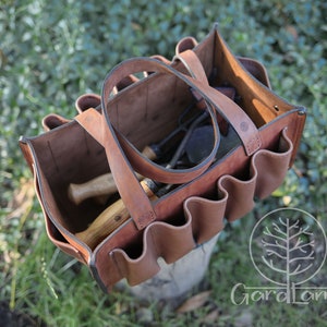 May include: A brown leather tool bag with multiple pockets and a handle. The bag is open and filled with gardening tools.