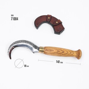 Puede incluir: Una hoja curva plateada con mango de madera y detalles en lat&oacute;n. La hoja tiene 80 mm de di&aacute;metro y el mango 140 mm de largo. Incluye una funda de cuero marr&oacute;n. SKU: 71084.