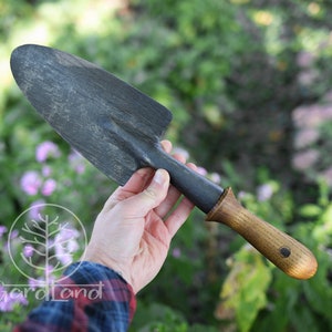 May include: A black gardening hand trowel with a wooden handle. The handle has a dark brown finish and a circular metal accent.