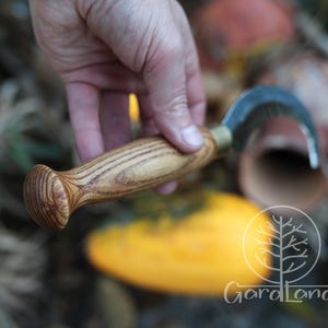 Puede incluir: Un cuchillo de jard&iacute;n curvo con mango de madera. La hoja met&aacute;lica tiene forma curva. El mango de madera tiene un extremo redondeado. El cuchillo est&aacute; dise&ntilde;ado para la cosecha y trabajos de jardiner&iacute;a.