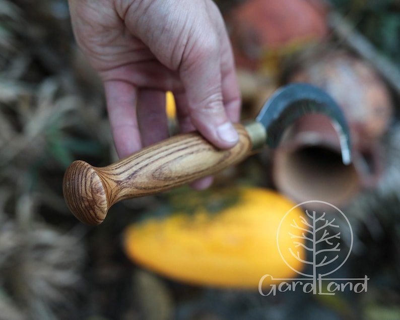 Puede incluir: Un cuchillo de jard&iacute;n curvo con mango de madera. La hoja met&aacute;lica tiene forma curva. El mango de madera tiene un extremo redondeado. El cuchillo est&aacute; dise&ntilde;ado para la cosecha y trabajos de jardiner&iacute;a.