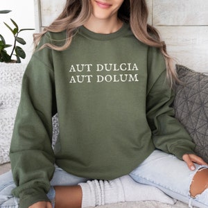 May include: A green sweatshirt with the Latin phrase "Aut dulcia aut dolum" printed in white on the front.