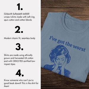 Op de afbeelding: Een lichtblauw T-shirt met de tekst "I've got the worst" in donkerblauw gedrukt. Het shirt heeft een blauwe illustratie van een vrouw met haar handen over haar oren.