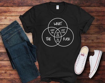 Könnte beinhalten: Schwarzes T-Shirt mit einem Venn-Diagramm-Design. Die Kreise zeigen die Wörter "WHAT", "THE" und "FUCK" in Weiß. Das T-Shirt wird mit blauen Jeans und weißen Turnschuhen kombiniert. Das Design ist humorvoll.