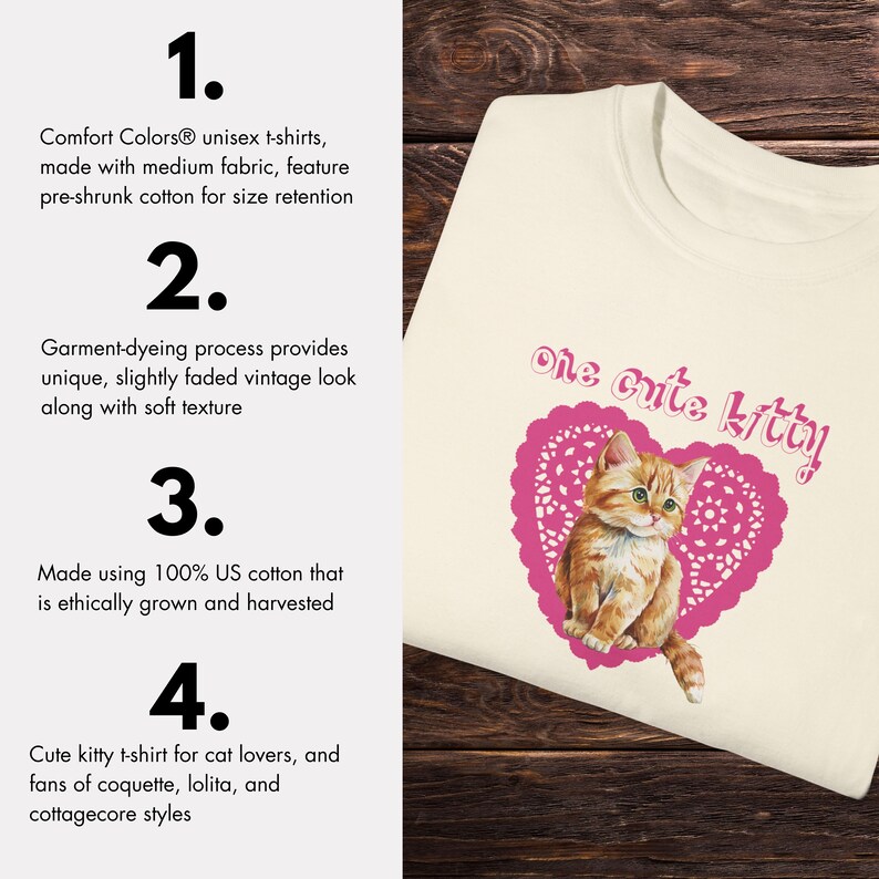 Op de afbeelding: Een wit T-shirt met een roze hartvormig ontwerp met een cartoon oranje tabby kat. De tekst "one cute kitty" is boven de kat gedrukt. Het T-shirt is gemaakt van 100% Amerikaanse katoen en is voorverkleind voor behoud van de maat.
