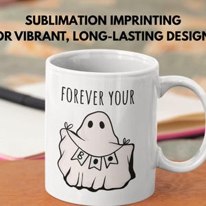 May include: White ceramic mug with a black ghost illustration holding a banner that says "B A E". The mug has the words "FOREVER YOUR" above the ghost. The text "SUBLIMATION IMPRINTING FOR VIBRANT, LONG-LASTING DESIGNS" is at the top.