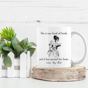 May include: White ceramic mug with a black and white illustration of a woman reading a book. The mug has the text "She is too fond of books and it has turned her brain. Louisa May Alcott" printed on it.