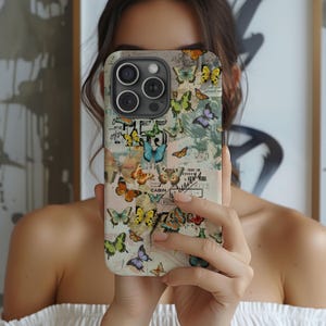 May include: A white phone case with a collage of vintage postcards and butterflies. The case features a variety of colors, including blue, green, yellow, and red. The text on the postcards is mostly illegible.