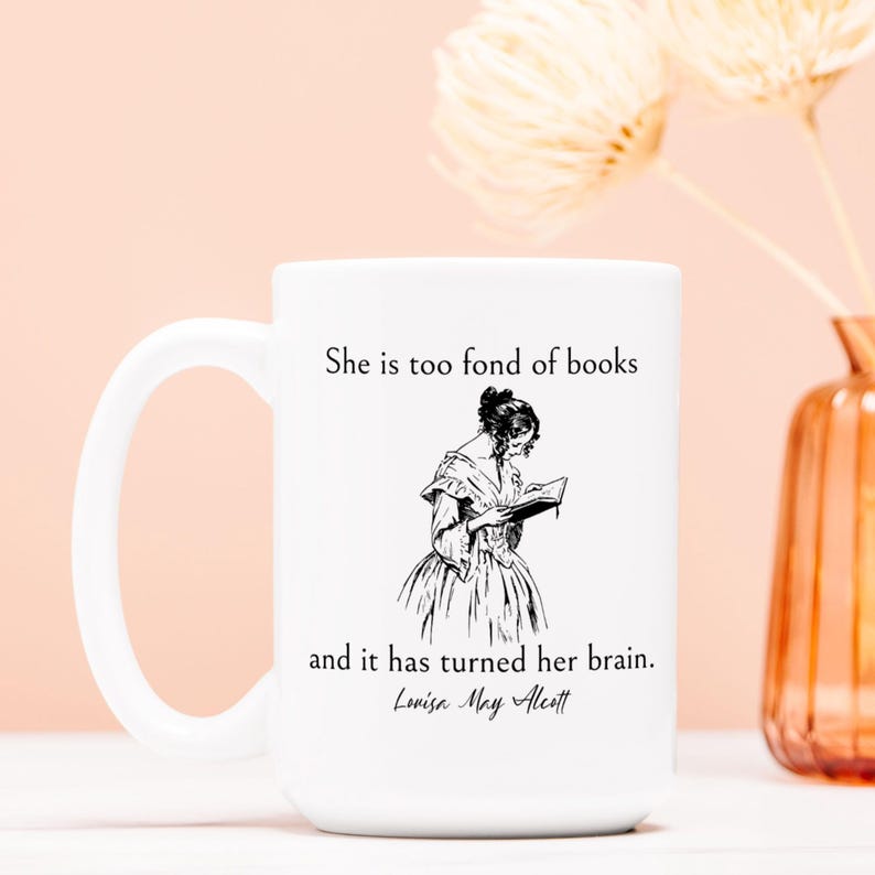 May include: White ceramic mug with a black and white illustration of a woman reading a book. The mug has the text "She is too fond of books and it has turned her brain. Louisa May Alcott" printed on it.